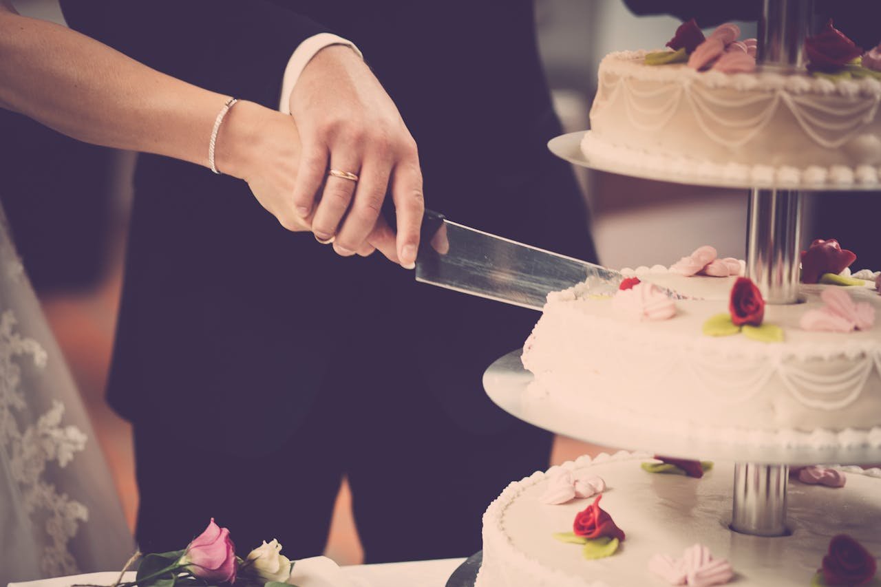 Bride and groom cutting a tiered wedding cake adorned with floral decorations, symbolizing celebration.
