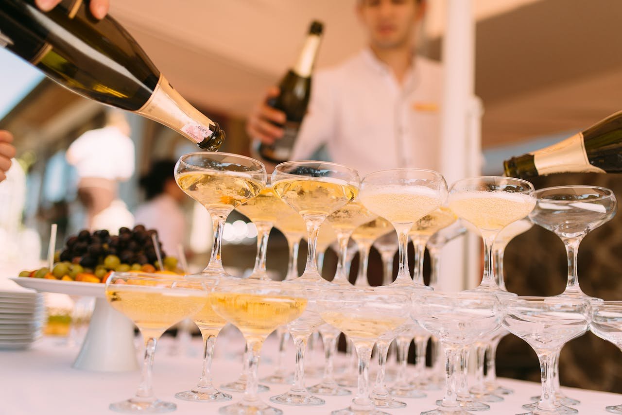 Champagne being elegantly poured into glasses at a festive celebration outdoors.