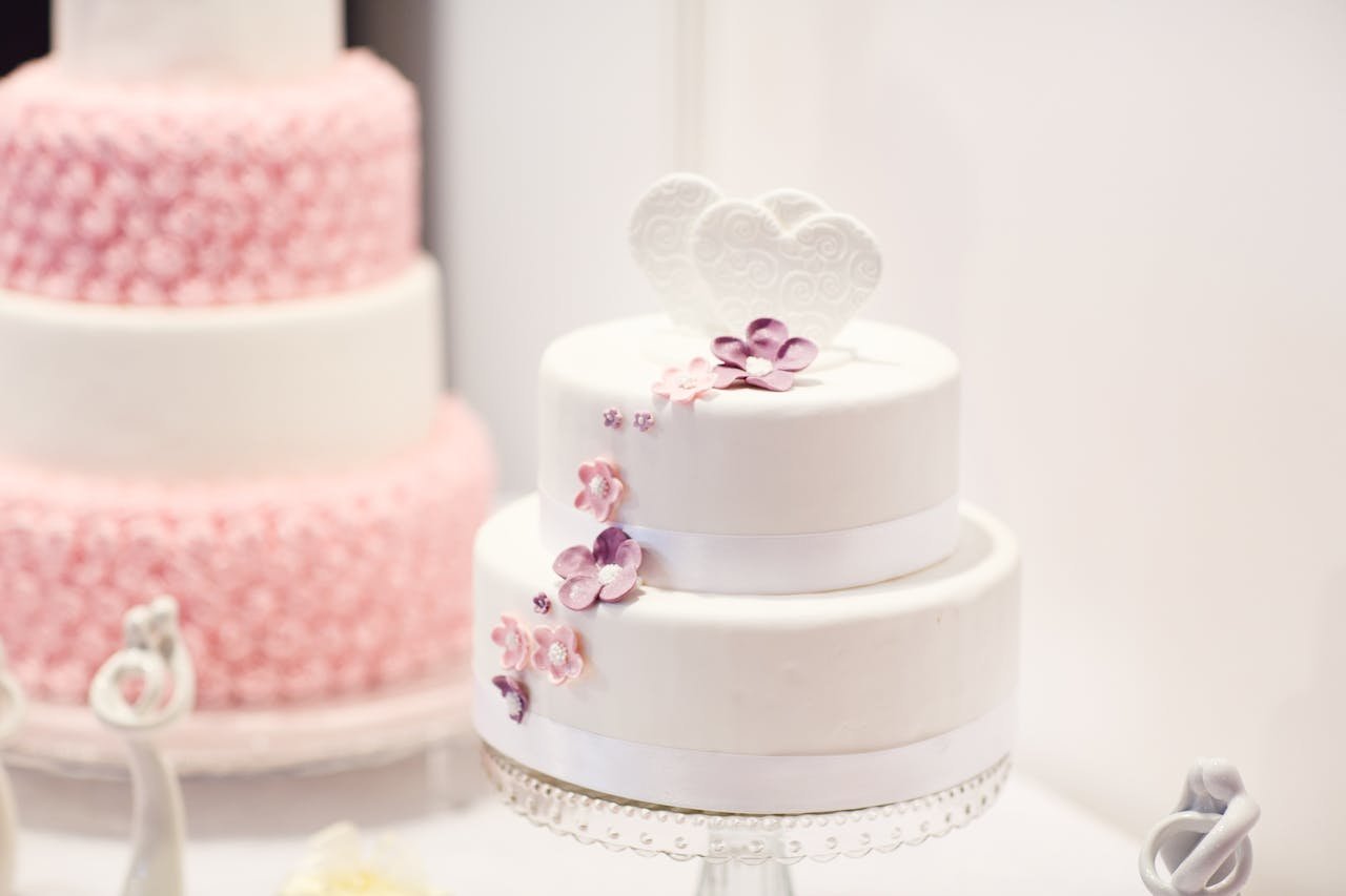 A beautifully decorated white wedding cake with elegant floral designs, perfect for weddings.