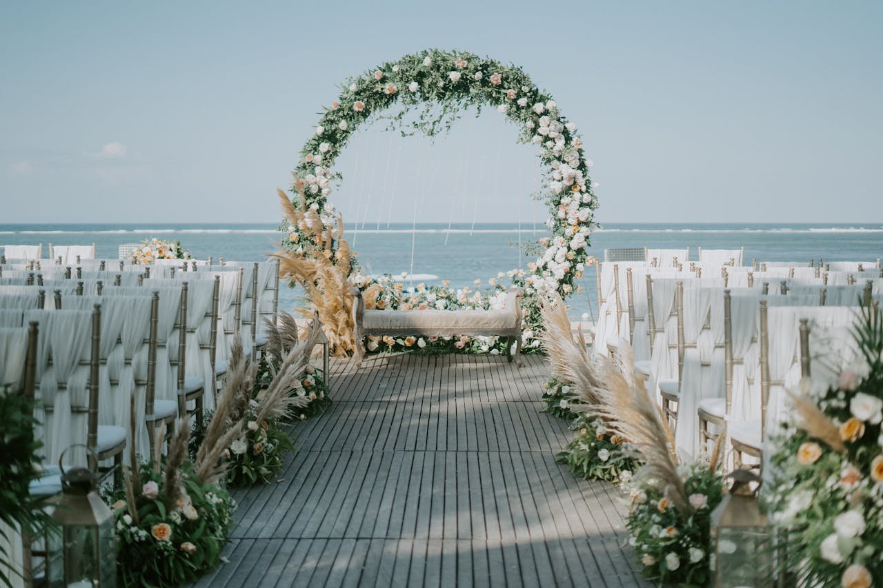 Beautiful beachside wedding setup with elegant floral arch and ocean backdrop.