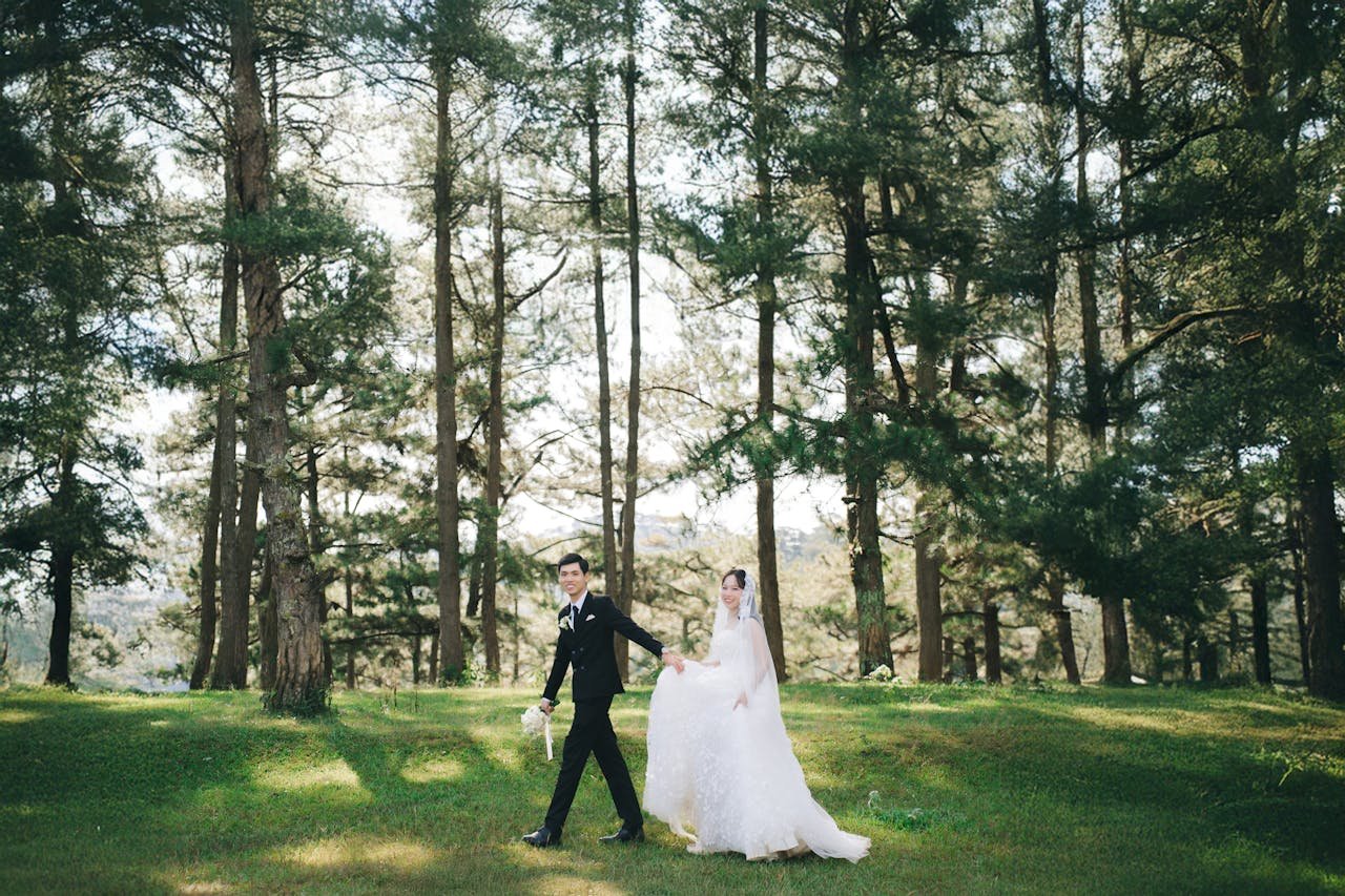 Bride and groom walking through a lush green forest on their wedding day.